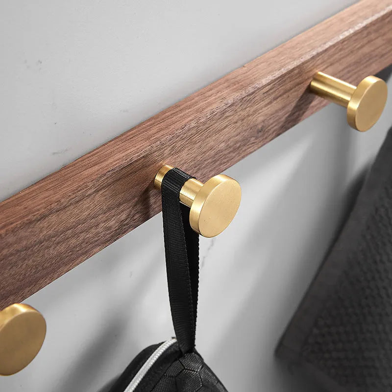 Black walnut wood hooks mounted on a perforated aluminium plate for bathroom towel hanging.
