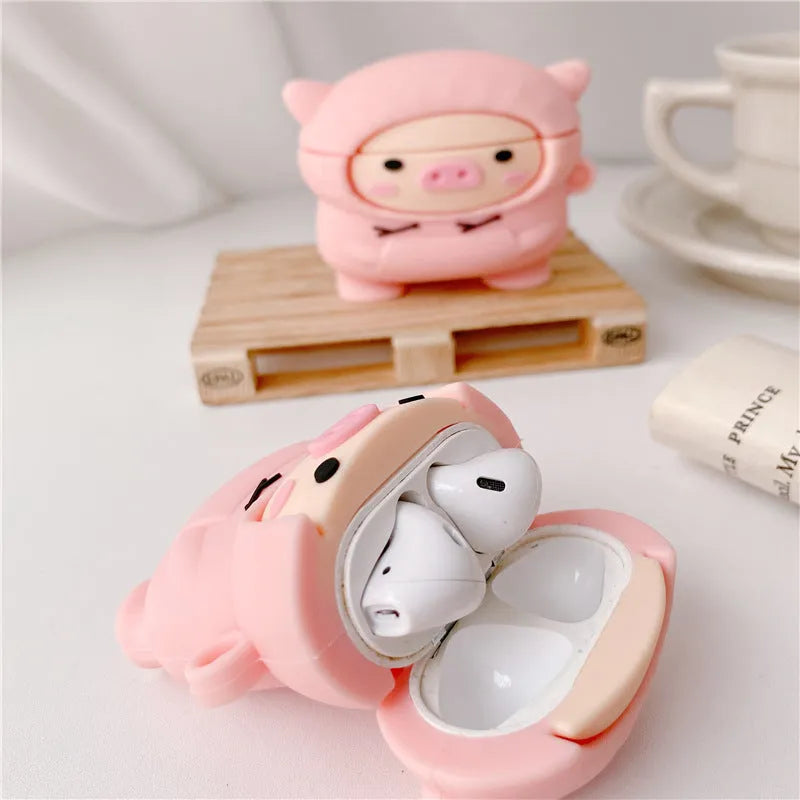 Pink silicone flip case with a cartoon pig design for AirPods and AirPods Pro, shown with a keychain hook.