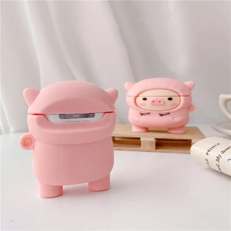 Pink silicone flip case with a cartoon pig design for AirPods and AirPods Pro, shown with a keychain hook.