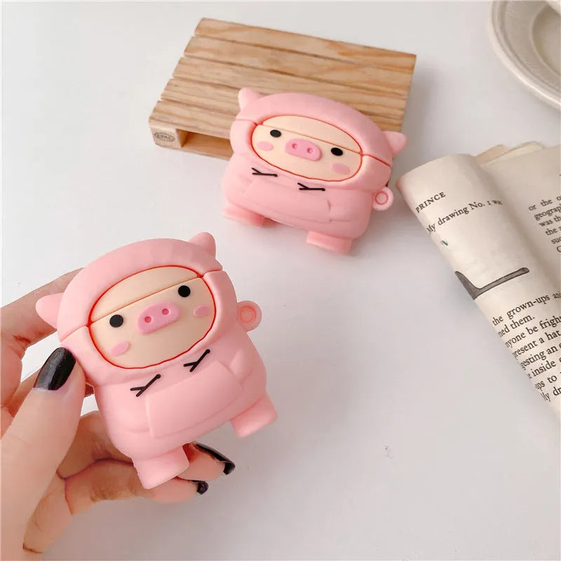 Pink silicone flip case with a cartoon pig design for AirPods and AirPods Pro, shown with a keychain hook.