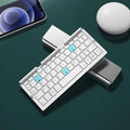 Silver aluminium folding Bluetooth keyboard with stand holding smartphone
