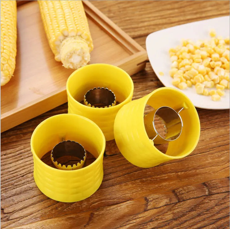 Yellow manual corn grinder thresher with corn kernel shaped grip on a kitchen worktop.