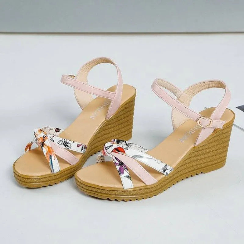 Women's pink wedge sandals with a thick heel, fish mouth toe, and an adjustable buckle strap.