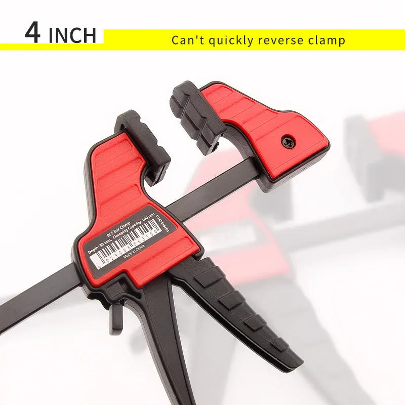 Black plastic quick release woodworking clamp with rubber jaws in multiple sizes on a workshop bench.