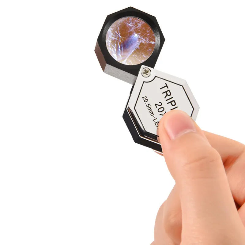 Handheld portable magnifying glass with metal body and optical glass lens for jewellery and coin inspection.