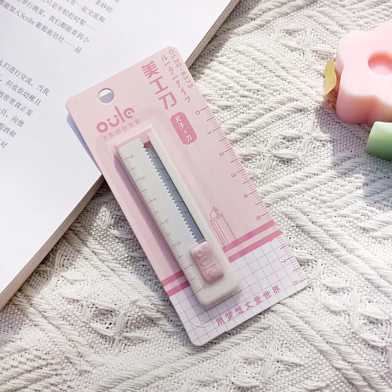Small plastic art knife in one of five colours: pink, blue, purple, khaki, or orange.