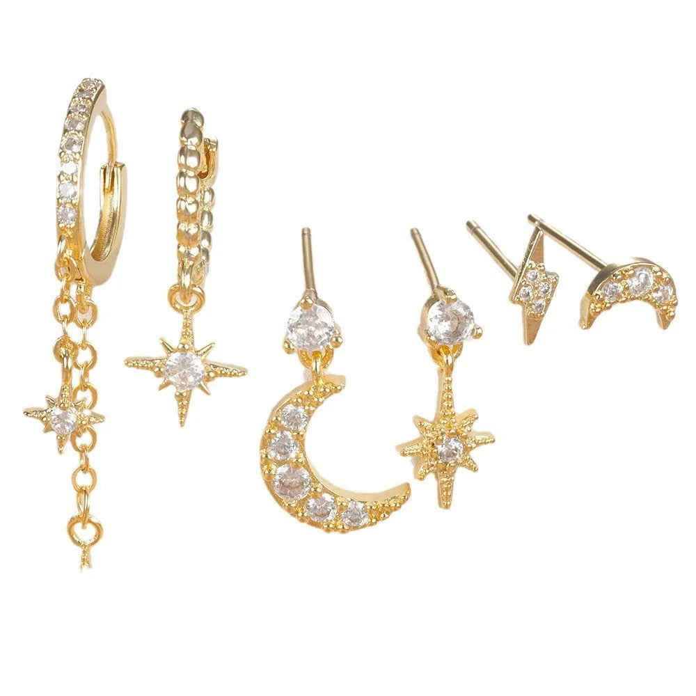 Set of six gold electroplated earrings with zircon studs and chain tassels on a flat surface.