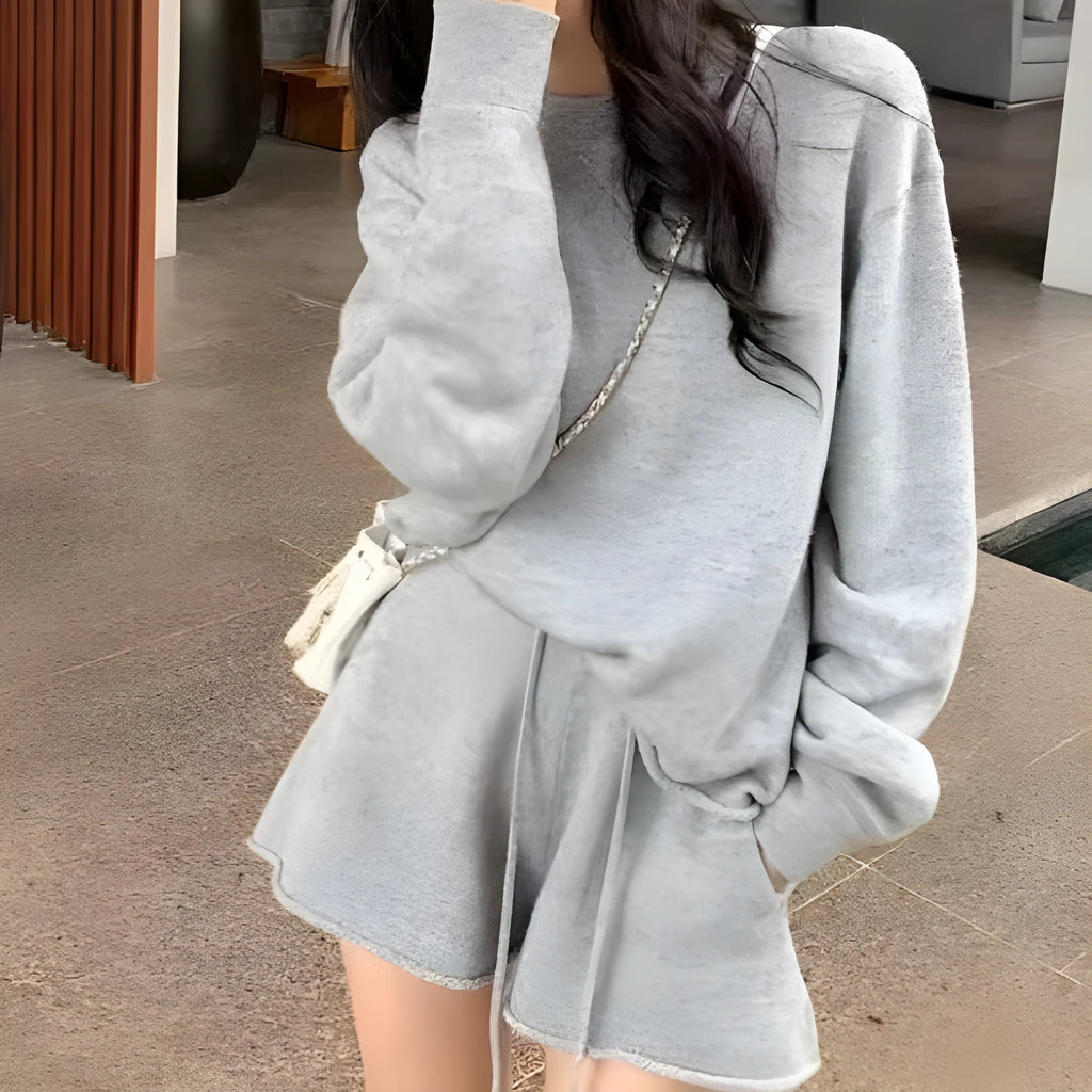 Woman wearing a loose grey long sleeve sweater and matching wide leg knit shorts lounge set.
