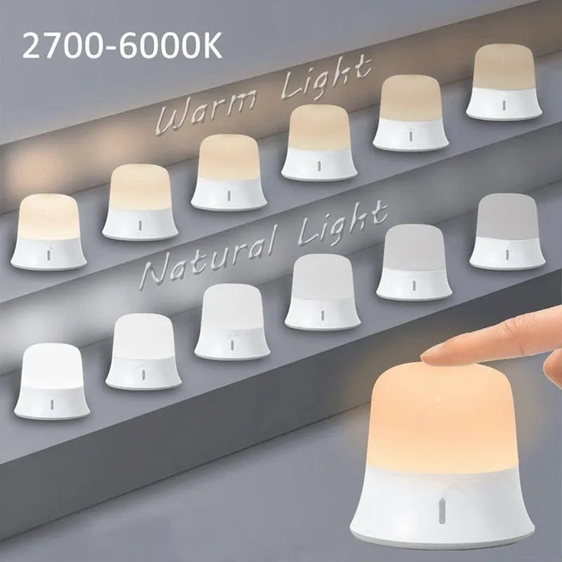 White baby night lamp with touch controls for dimming and colour change on a bedside table.