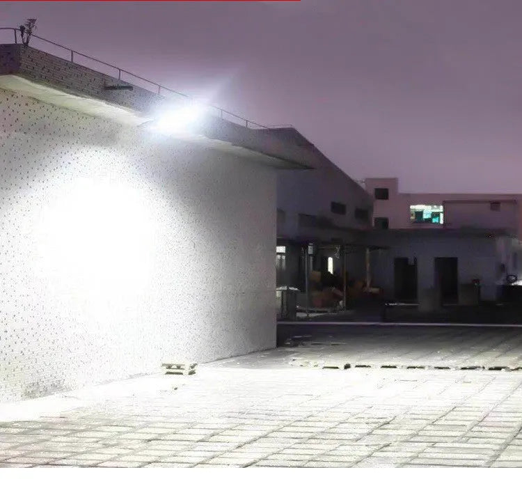 Black outdoor solar-powered motion sensor security light with solar panel on top.
