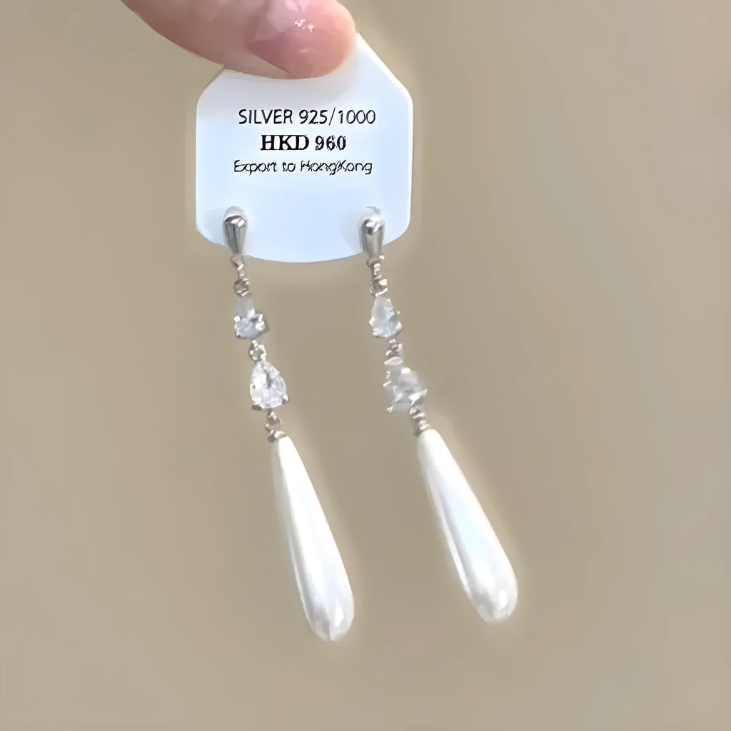 Women's geometric heart-shaped earrings with rhinestones and a dangling tassel, shown in silver tone.