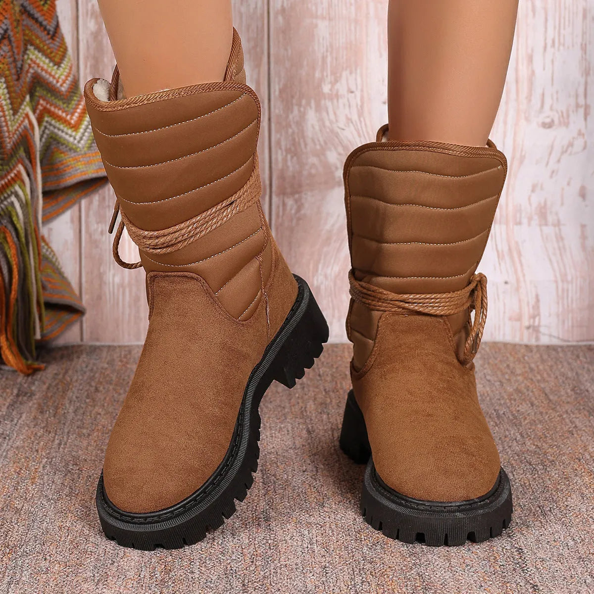 Women's black suede chunky heel snow boots with lace-up front and fleece lining shown on a winter background.