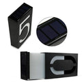 Solar powered illuminated house number light with white LEDs mounted on a wall.