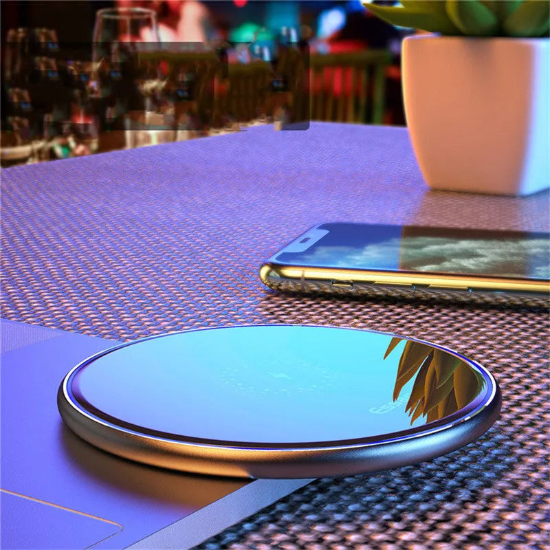 Black or white aluminium alloy wireless charging pad with LED status light on desk.