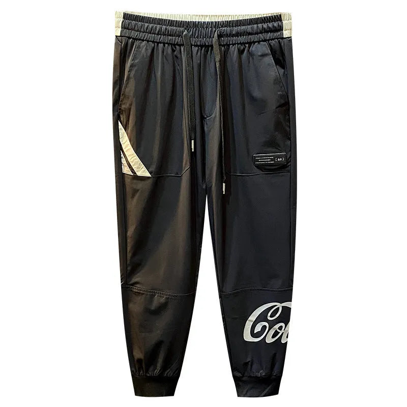 Black cotton men's cropped casual trousers with a banded ankle cuff laid flat.