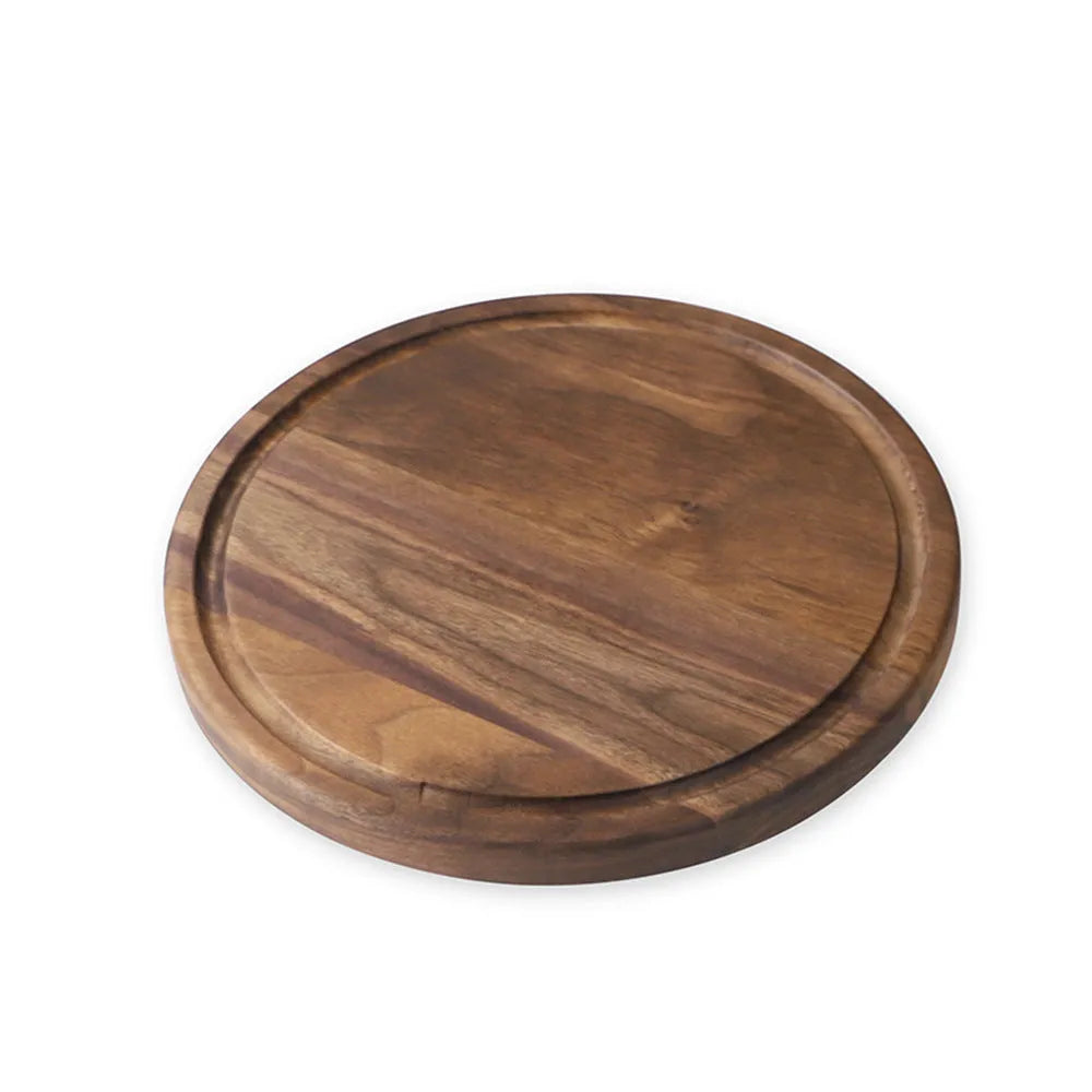 Solid black walnut wood cutting board with juice groove and side handle on a kitchen counter