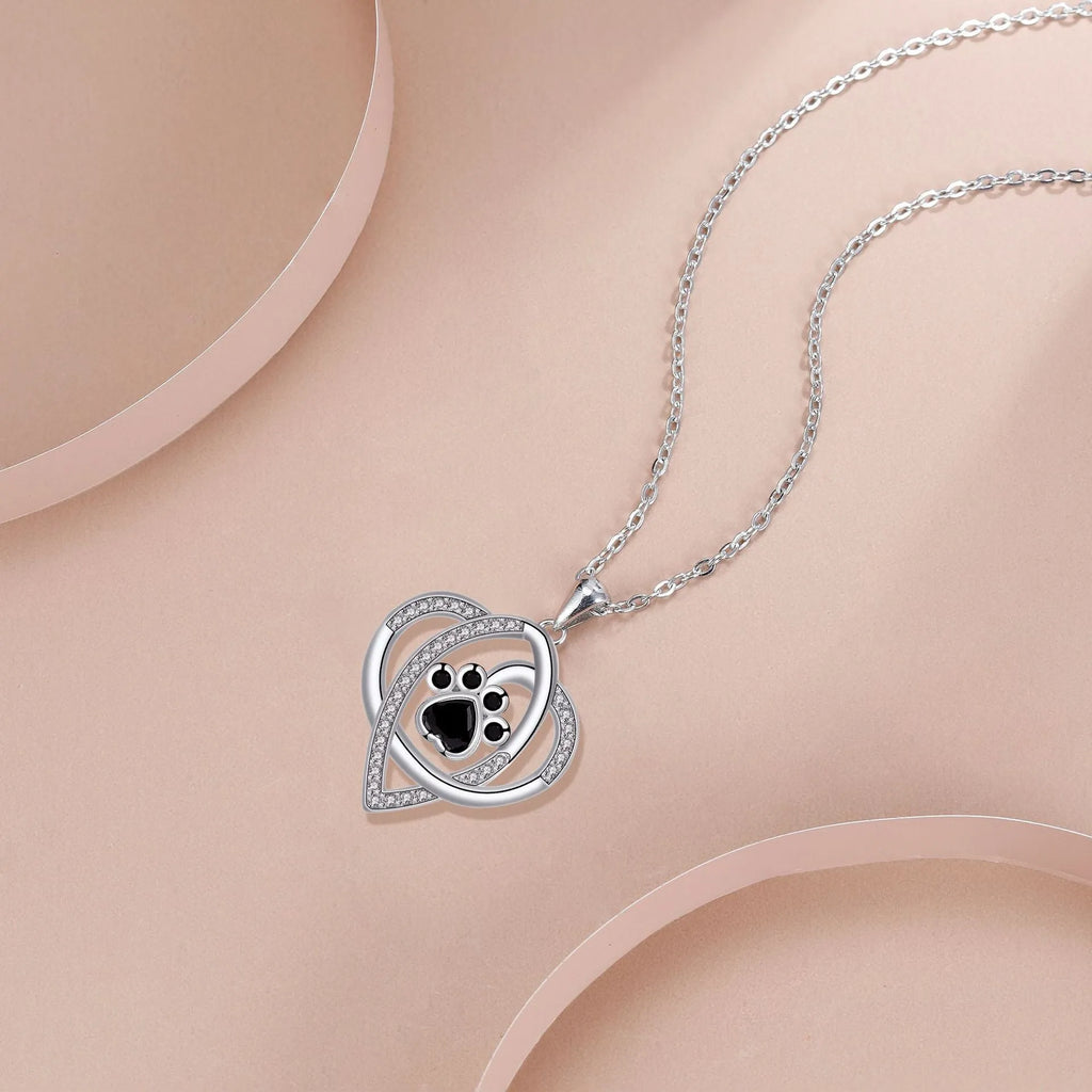 Light gold necklace with a pendant showing raised dog and cat paw prints on a cross chain.
