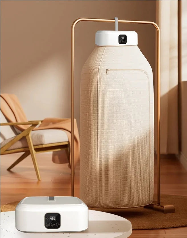 White cylindrical portable mini clothes dryer with remote control on a table.