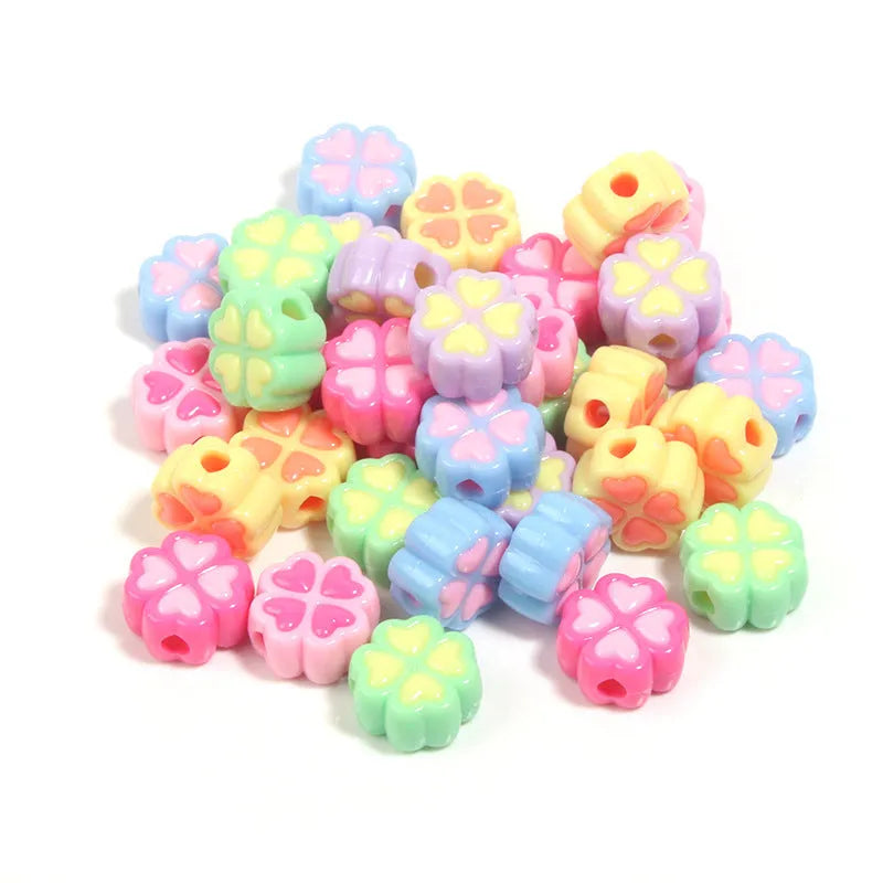 Assortment of frosted acrylic love clover beads in mixed colours on a white background.