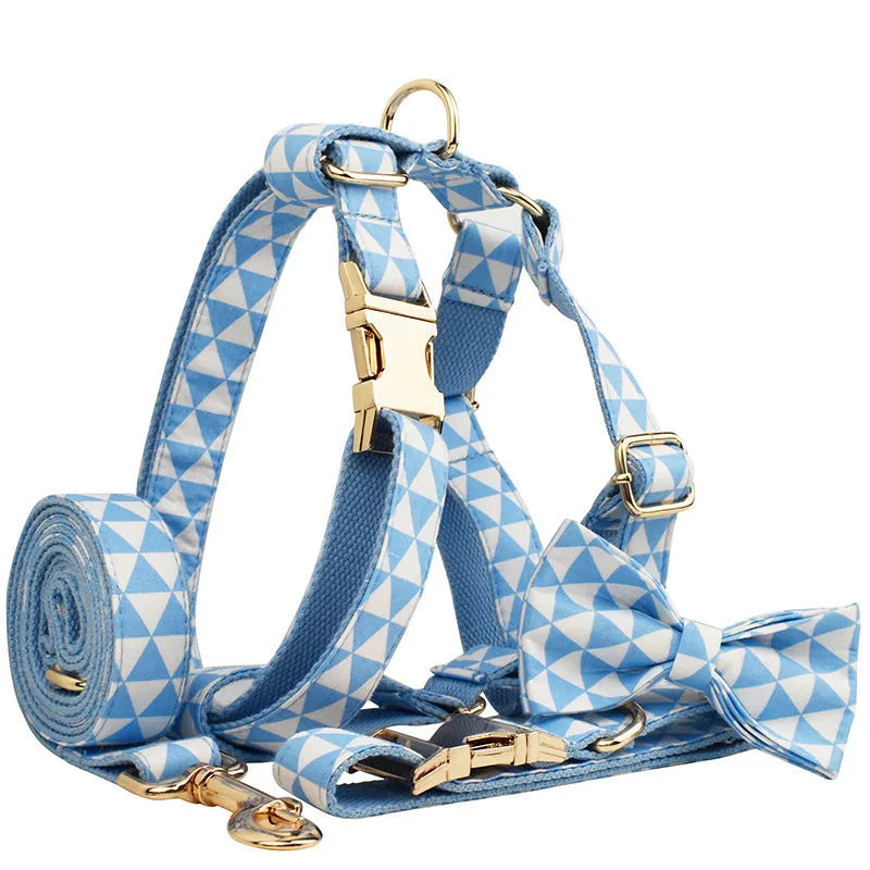 Blue cloth dog vest, matching collar with triangular ring, rope leash, and decorative bow laid out as a four-piece set.