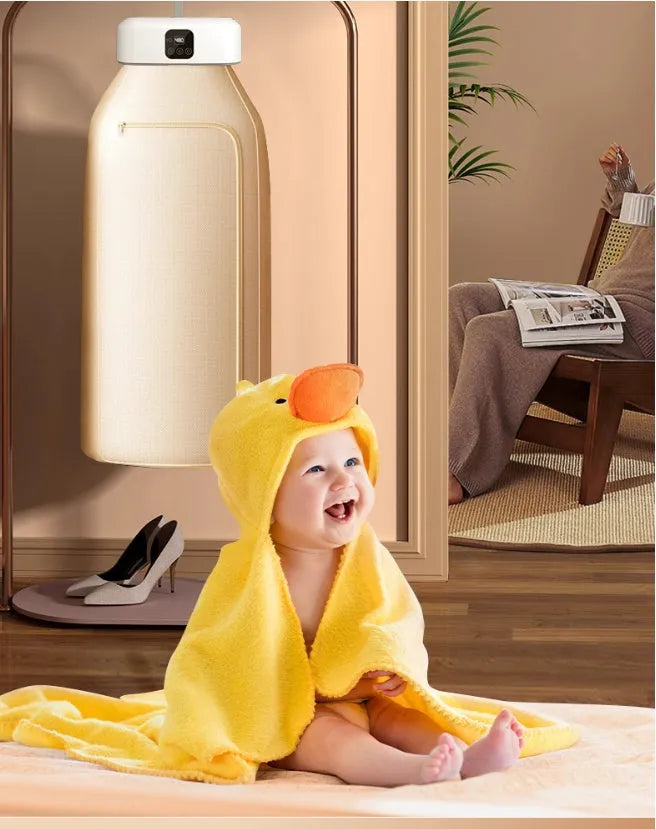 White cylindrical portable mini clothes dryer with remote control on a table.