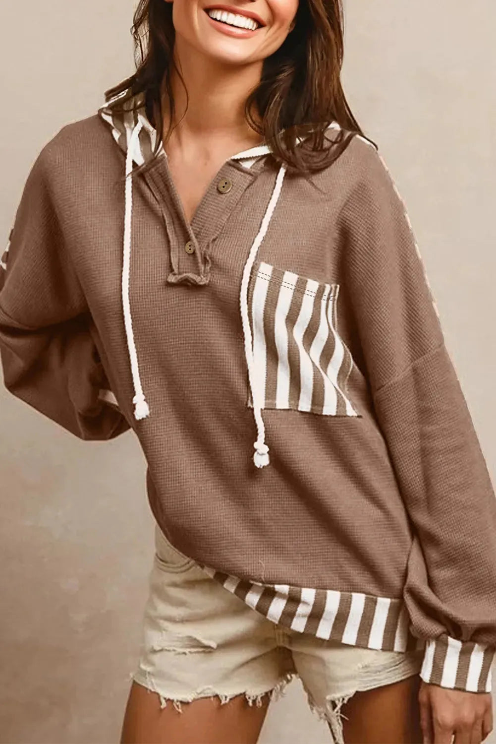 Straw yellow hoodie with waffle texture fabric and striped patchwork panels, featuring a drawstring hood and button neck.