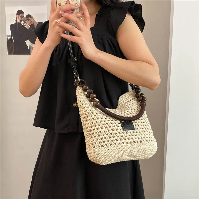 Knitted crossbody tote bag in bucket shape, shown in black with contrast stitching and a zippered internal pocket.