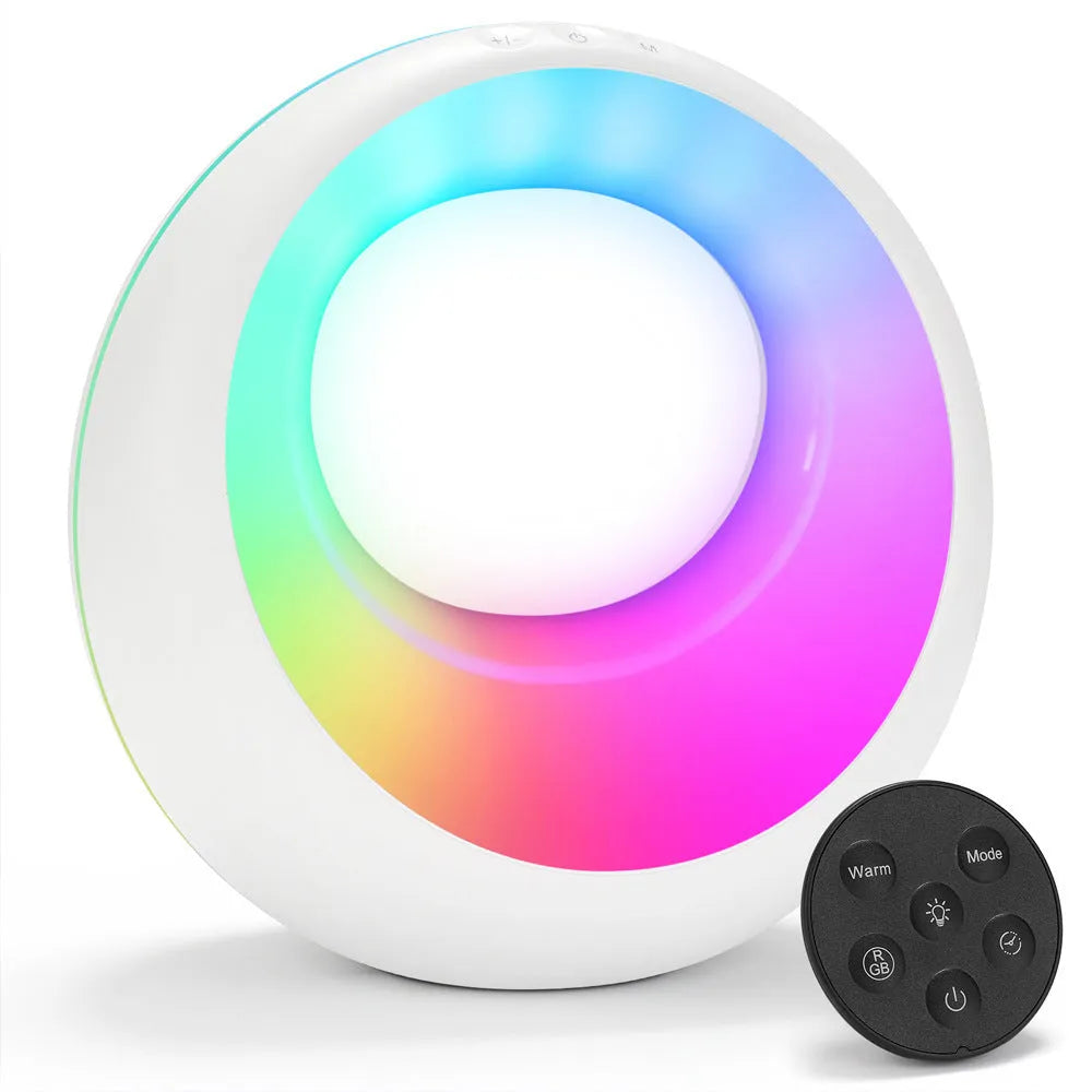 Small white RGB colour changing desk lamp with remote control on a wooden surface.