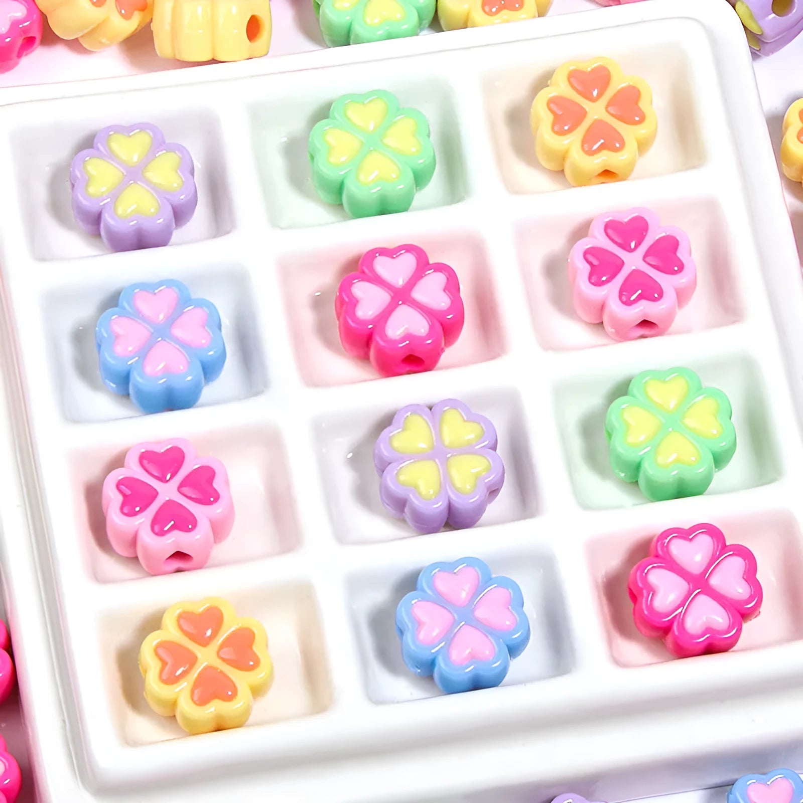 Assortment of frosted acrylic love clover beads in mixed colours on a white background.