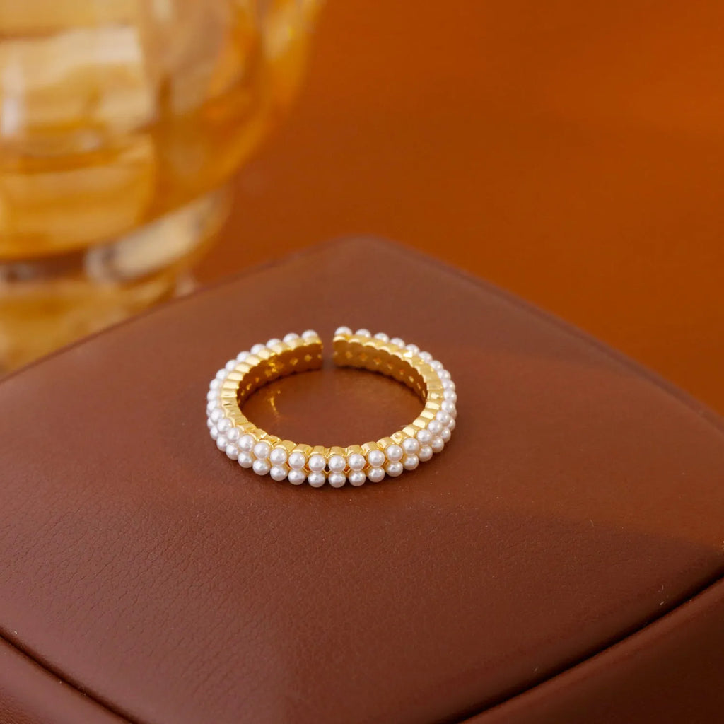 Gold geometric open ring with pearl detail on a model's finger.