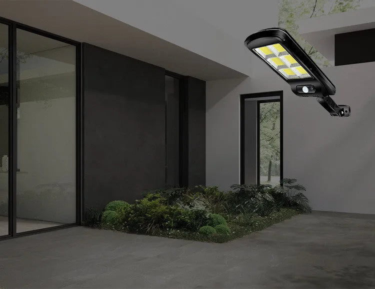 Black outdoor solar-powered motion sensor security light with solar panel on top.