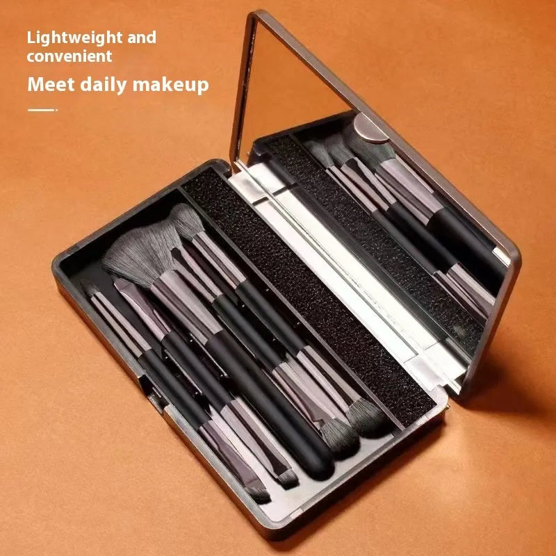 Makeup brush kit with built-in mirror showing silver or gold plastic handles and artificial fibre bristles