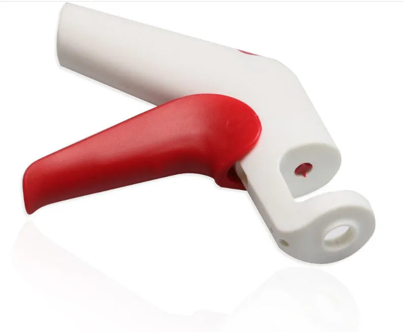 Stainless steel manual cherry pitting tool with ergonomic handle on a wooden surface.