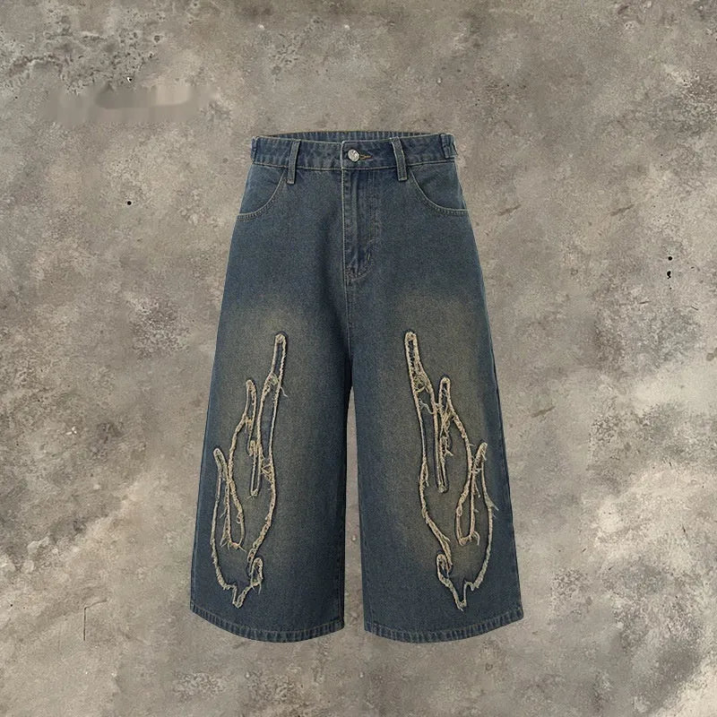 Men's black cropped denim shorts with flame embroidery patch detail on straight leg silhouette