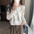 Women's milky white long-sleeved acrylic cardigan coat worn open as a layer.
