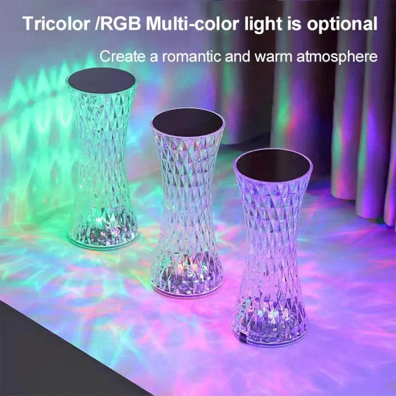 Transparent crystal vase shaped LED table lamp with remote control on a wooden bedside table.