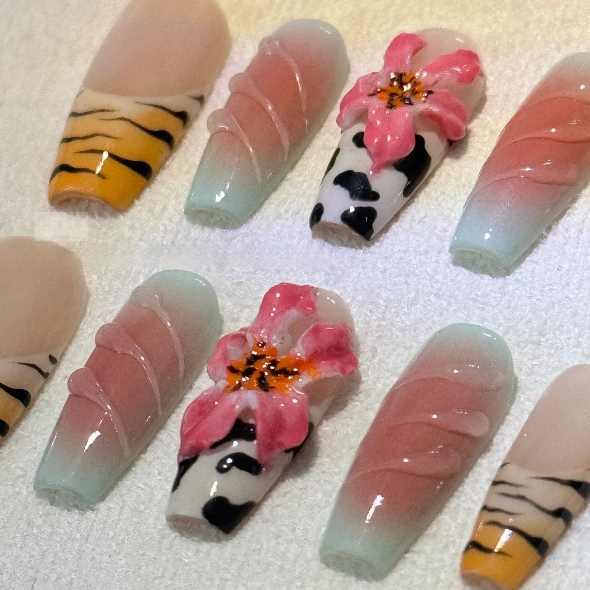 Zebra pattern and Lily hand carved nail art with flower and leopard print designs on a clear background.
