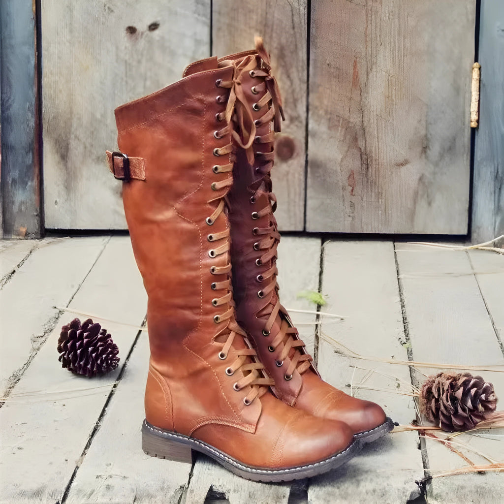 Black chunky heel high leg boot with round toe and low rubber sole on a plain background.