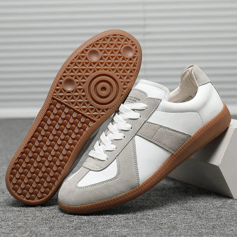 White low-top retro unisex sneakers with round toe and lace-up front on a plain background.