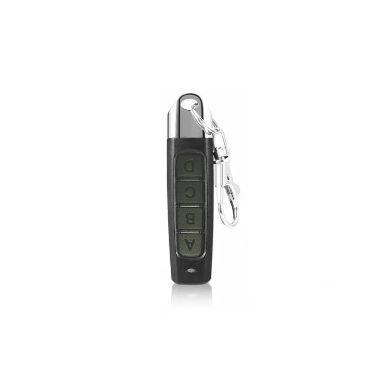 Compact black programmable remote control for rolling doors with copy button, shown next to a 12V battery.