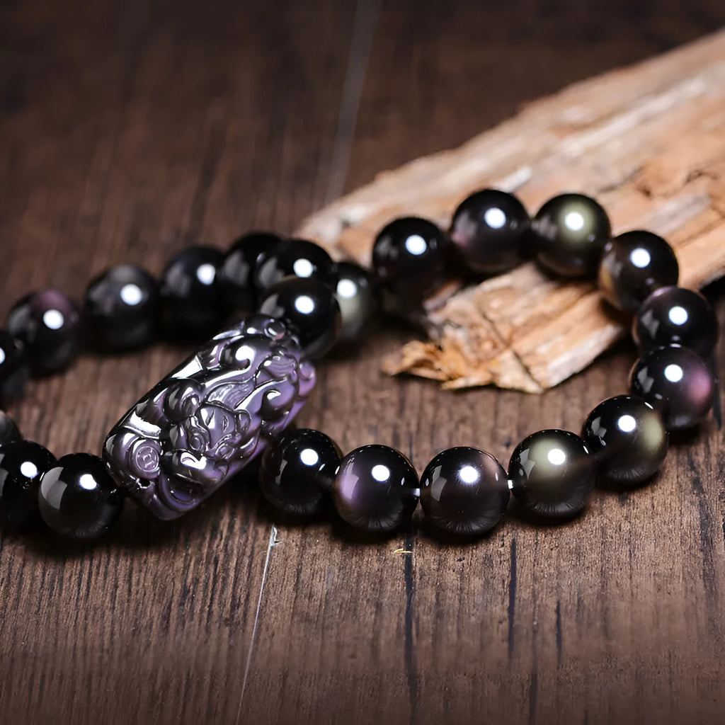 Polished crystal Pi Xiu bracelet with icy obsidian stone on wrist, showing geometric ethnic style.