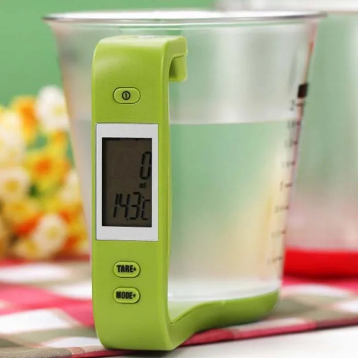 Green electronic kitchen scale measuring cup with LCD display built into handle showing weight measurement