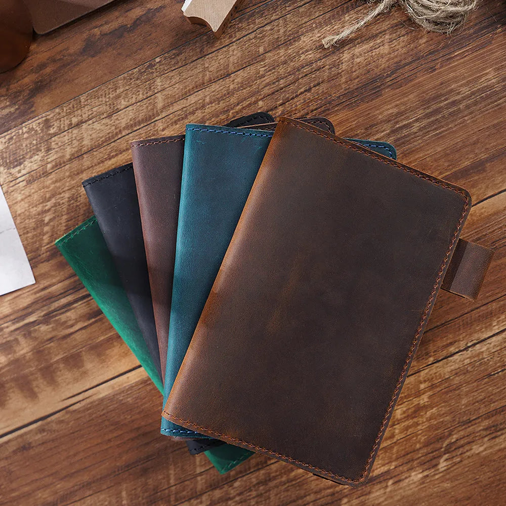 Handmade notebook with cowhide cover open on a table, showing 100 gsm wood-free paper inside
