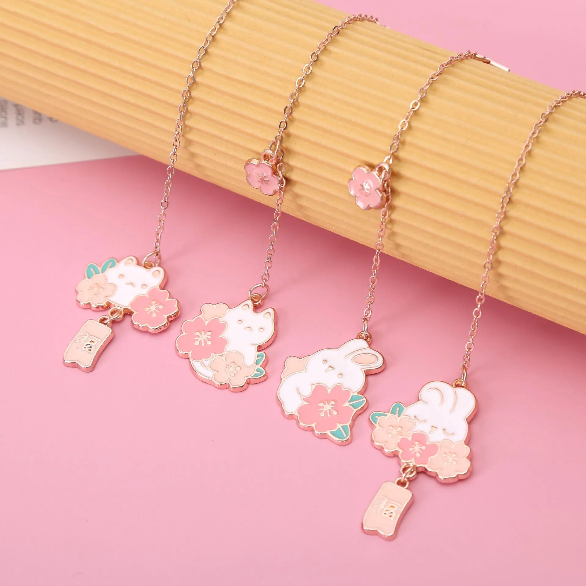 Small metal pendant bookmark with cartoon Sakura cat or cherry blossom rabbit illustration.