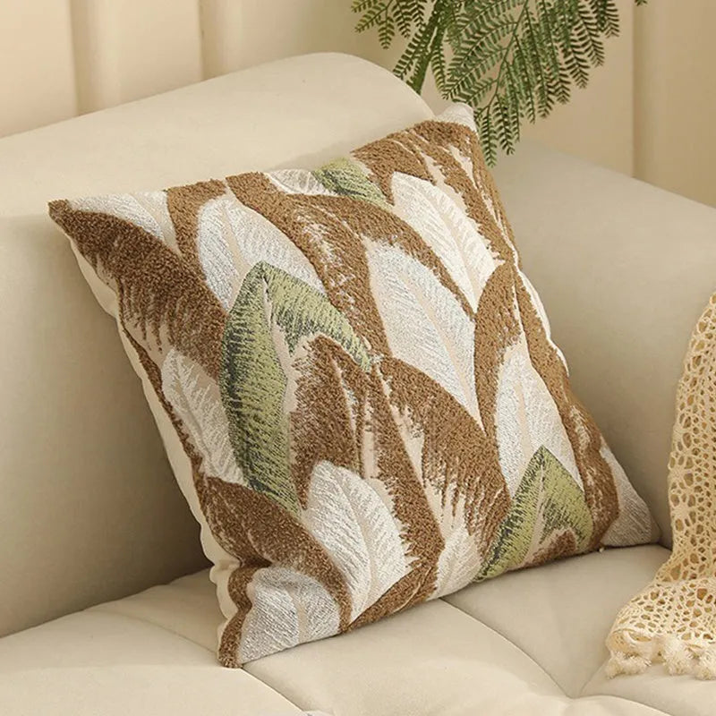 Square jacquard pillow cover with botanical pattern on a sofa, showing one of eight available colour options.