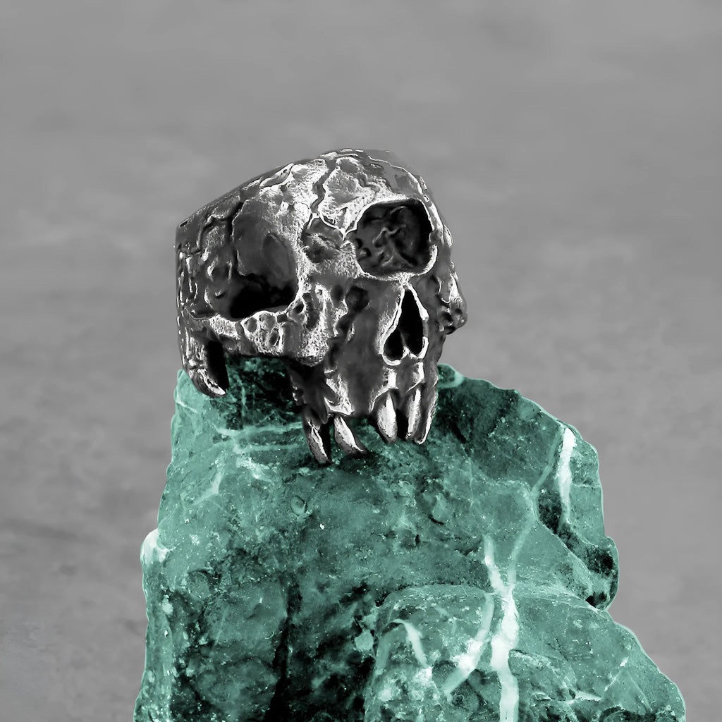 Close-up of a silver-toned alloy ring with a detailed one-eyed skull design on a black background.