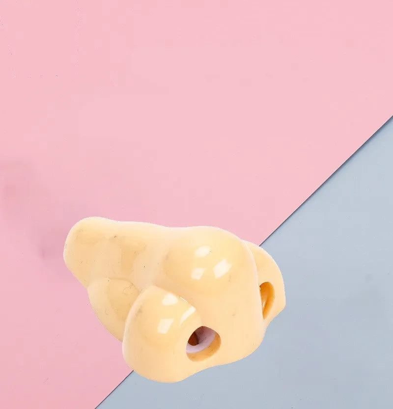 Flesh colour plastic geometry pencil sharpener with big nostril design on a white background.