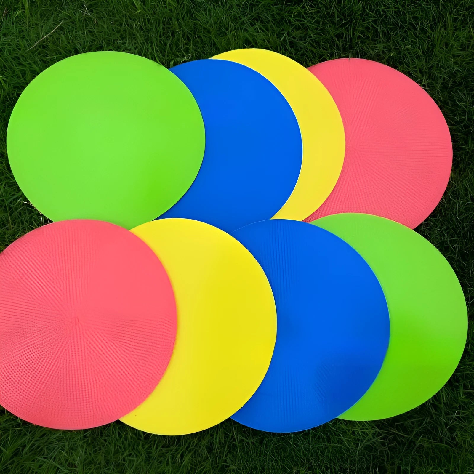 Yellow TPE football training marker disc lying flat on grass, 23cm diameter.