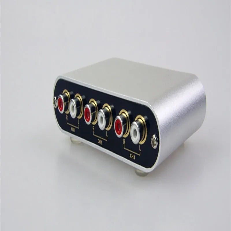 Silver audio source selector switch unit with infrared remote control for routing multiple audio signals.