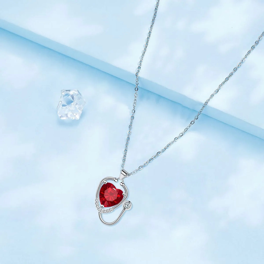 Women's fashion necklace with a copper wings cross stethoscope pendant featuring red diamond detail.